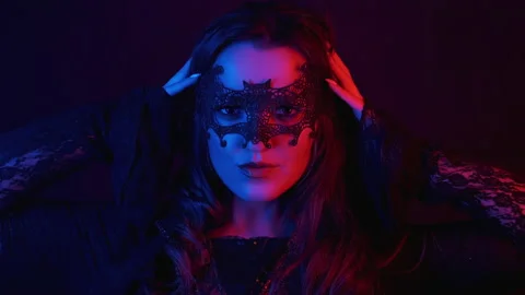 Magic witch in cloak looking at camera at dark background on halloween. Stock Footage 136024019