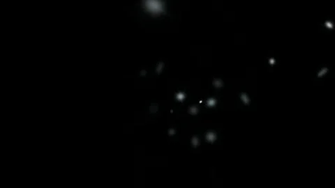 Magical glowing particles drift through dark space creating a dreamy, ethereal Stock Footage 314886089