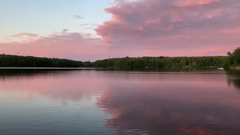 Magical red sunset mirrored and reflecting over calm cottage lake Stock Footage 225355331
