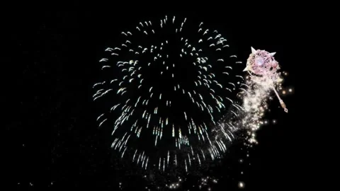Magical wand casting shimmering light particles and fireworks against dark Stock Footage 345330842