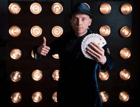 Magician in black suit standing in the room with special lighting at backstag Stock Photos