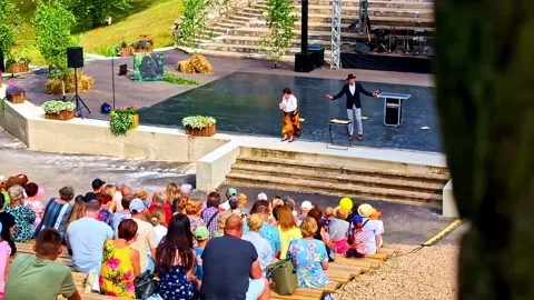 Magician captivating a crowd with an illusion performance in an open-air theatre Stock Footage 334091337
