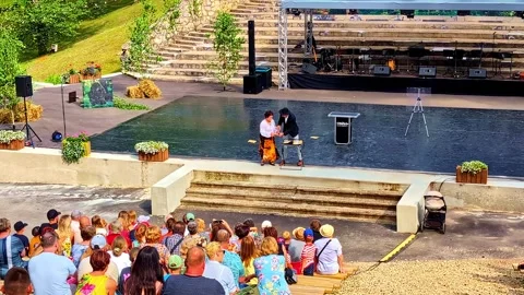 Magician performing magic trick on stage for an audience watching open-air show Stock Footage 334744771