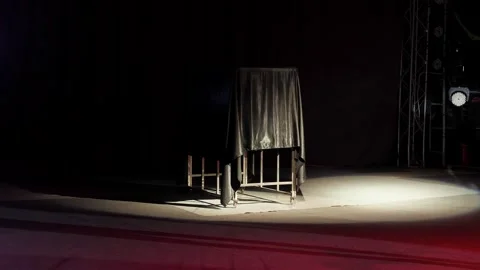A magician performs in a circus with a flashing light and a covered cage. Stock Footage 274930918
