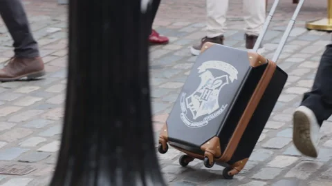 Magician pulls Hogwarts suitcase on cobblestone street in London Stock Footage 311110313