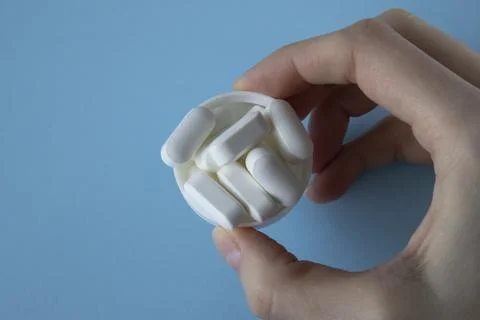 Magnesium Tablets. White tablets with rounded edges in a lid in a woman's hand Stock Photos