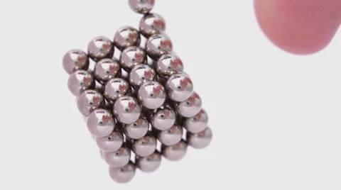 Magnet balls in cubic structure hangs, finger push it and cube begin to rotate Stock Footage