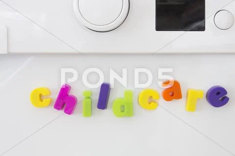 Magnetic letters on washing machine spelling childcare Stock Photos