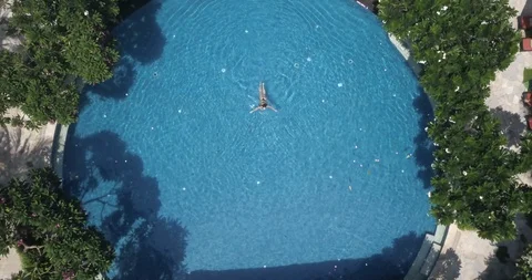 Magnificent view of circle swimming pool with woman swimming in it Stock Footage 129386403