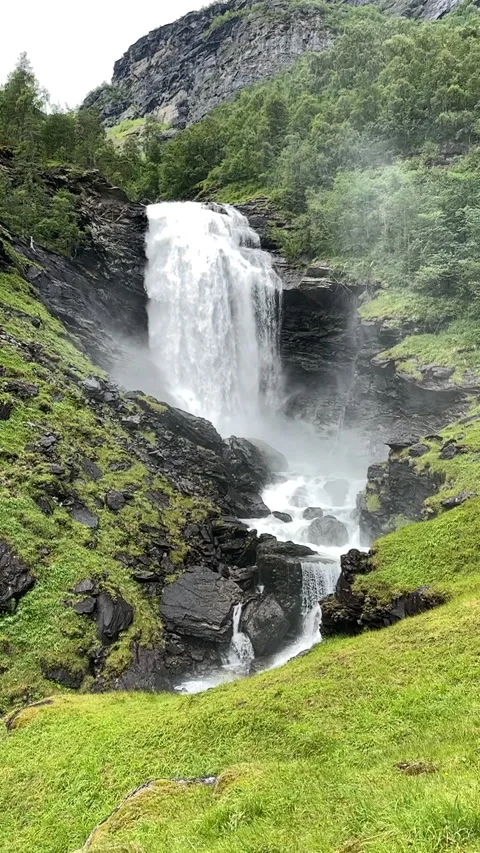 A magnificent waterfall pours down rugged rocks into a lush landscape, Video stock 314113357
