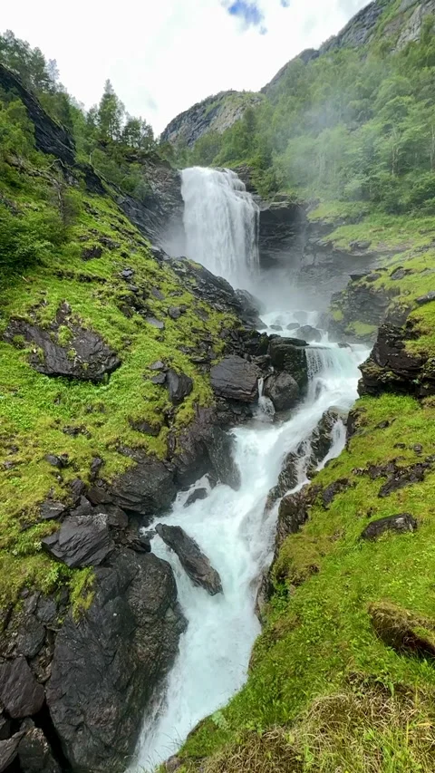 A magnificent waterfall pours down rugged rocks into a lush landscape, Stock Footage 314113382