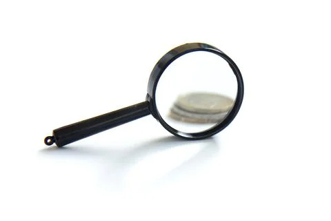 Magnifier and stack of coins isolated on white background Stock Photos