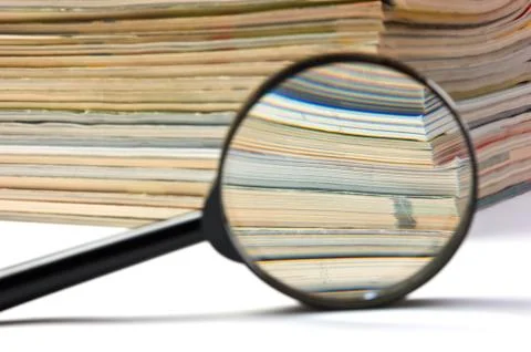 Magnifier and stack of magazines 库存照片
