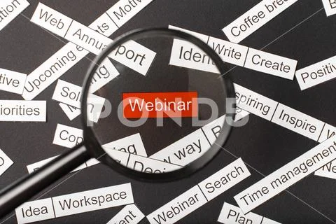 Magnifier glass over the red inscription webinar cut out of paper. Surrounded Stock Photos