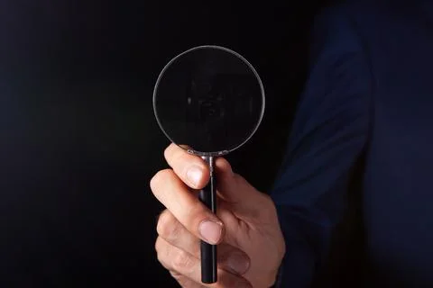 Magnifier in hand of a man Stock Photos