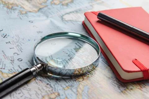 Magnifier, notebook and pen on map Stock Photos