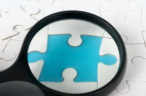 Magnifier on puzzle Stock Photos