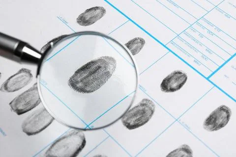 Magnifying glass and criminal fingerprint card, closeup Stock Photos