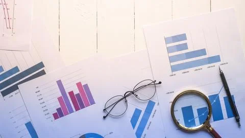 Magnifying glass and documents with analytics data lying on table,selective.. Stock Photos