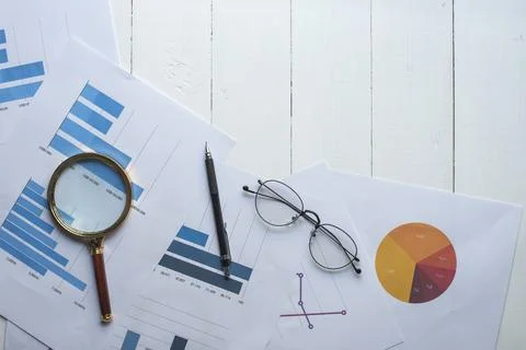 Magnifying glass and documents with analytics data lying on table,selective.. Stock Photos