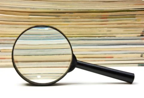 Magnifying glass and stack of magazines Foto stock