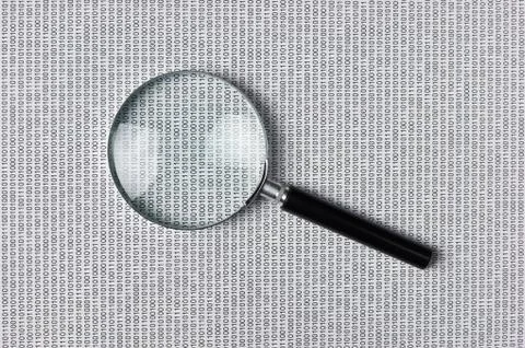 Magnifying glass on a binary code Stock Photos