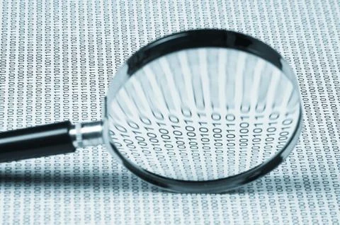 Magnifying glass on a binary code Stock Photos