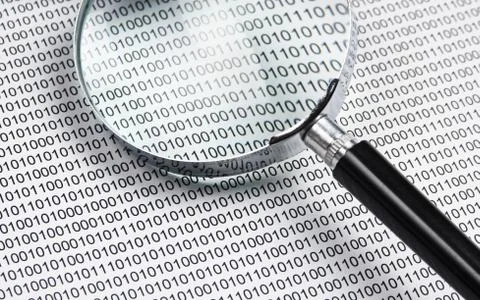 Magnifying glass on a binary code Stock Photos