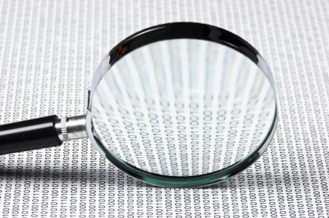 Magnifying glass on a binary code Stock Photos