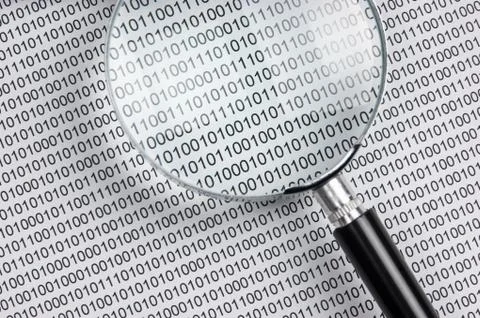 Magnifying glass on a binary code 写真素材