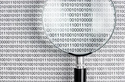 Magnifying glass on a binary code Stock Photos