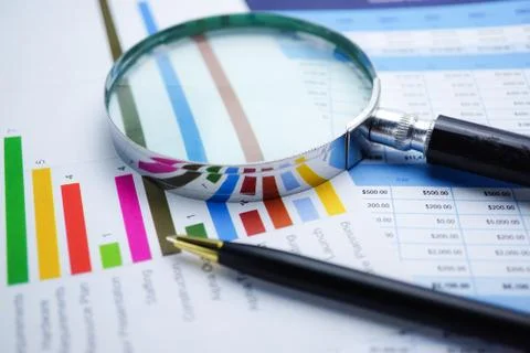 Magnifying glass on charts graphs spreadsheet paper. Stock Photos