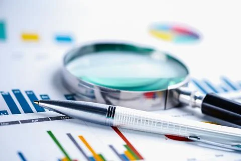 Magnifying glass on charts graphs spreadsheet paper. Financial development, B Stock Photos
