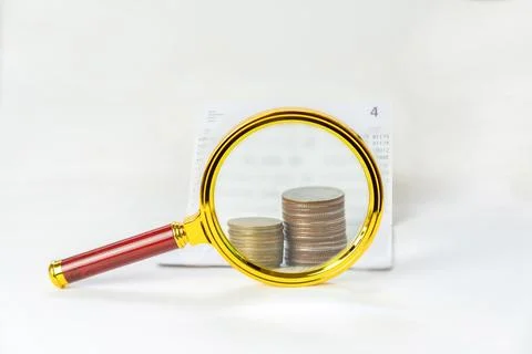Magnifying glass focus on stack of coins and book bank. Stock Photos