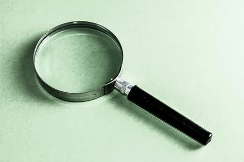 A magnifying glass is on a green surface Stock Photos