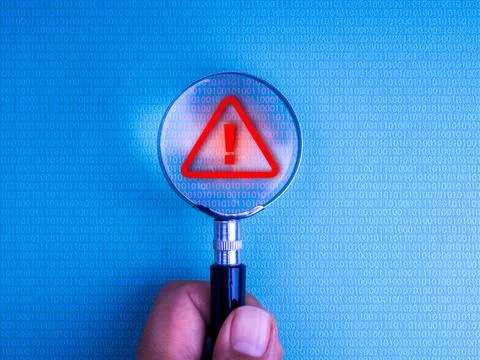 Magnifying glass in hand over binary code on computer screen detecting red .. 库存照片