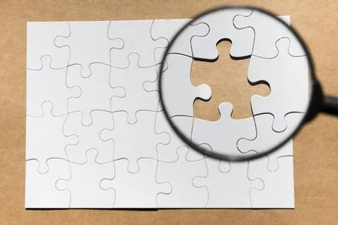 Magnifying glass missing puzzle brown paper textured backdrop Stock Photos