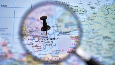 Magnifying glass over printed map focusing on Stockholm Fotos Stock