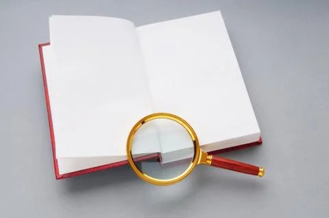 Magnifying glass over the stack of books Stock Photos