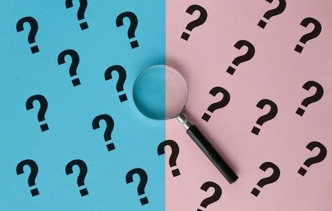 A magnifying glass is placed in the middle of a pattern of many questions Stock Photos