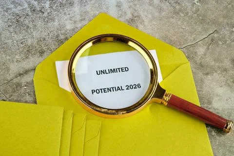 A magnifying glass rests atop a stack of bright yellow envelopes, focusing on a Foto stock