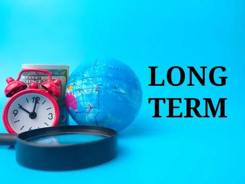 Magnifying glass,earth globe,banknotes and clock with text LONG TERM Stock Photos
