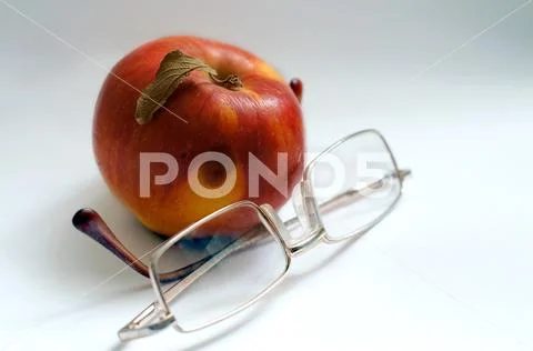 Magnifying glasses lie on a white background with a red ripe apple Stock Photos