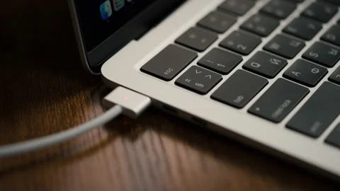 The MagSafe charger wire is connected to the MacBook Air. 스톡 동영상 231717095