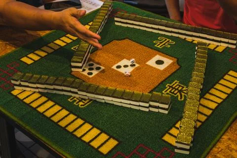 Mahjong Game Setup with Dice Rolling on Green Mat Stock Photos