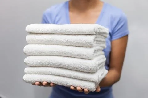 Maid holding a stack of white towels Stock Photos