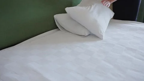 The maid in the hotel changes the bed linen and puts the pillows on the bed Stock Footage 283253933