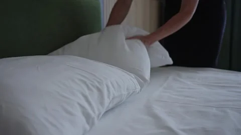The maid in the hotel changes the bed linen and puts the pillows on the bed Video stock 284206242