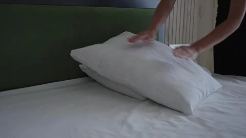 The maid in the hotel changes the bed linen and puts the pillows on the bed Stock Footage 286404610