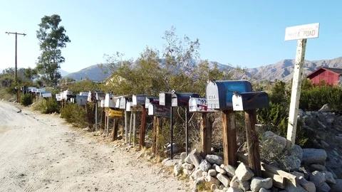 Mail boxes sit along the road side in the rugged California Desert Stock Footage 127545727